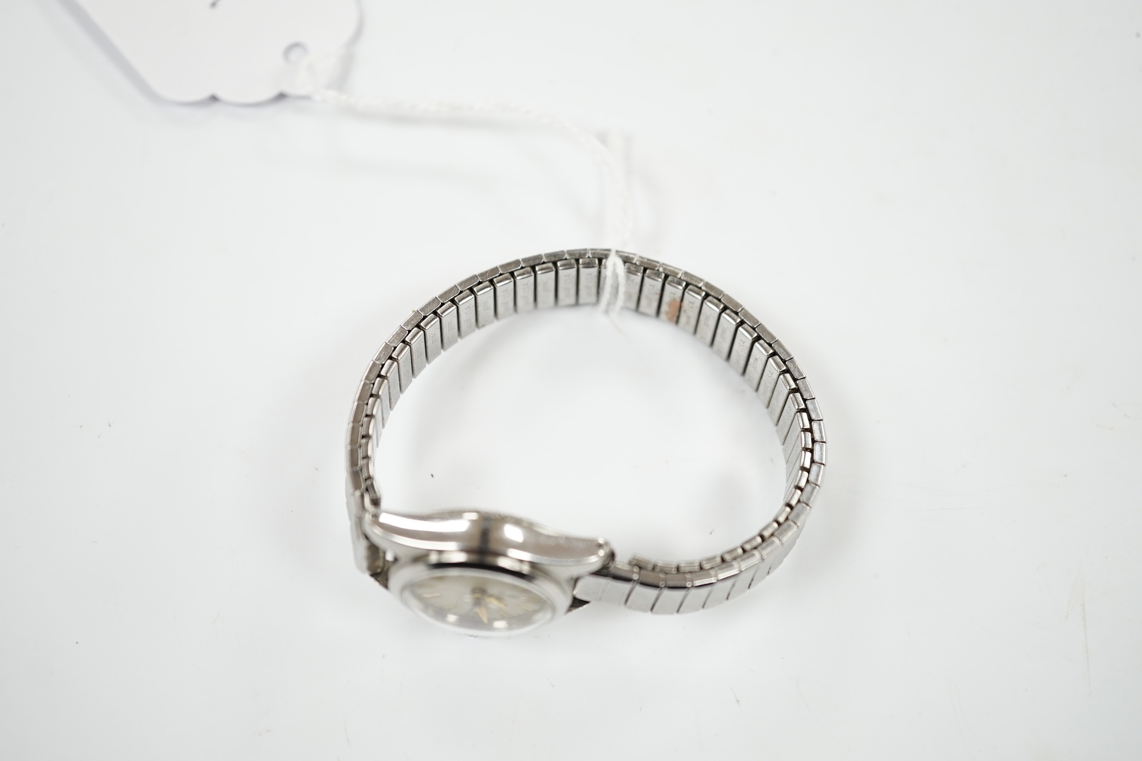 A lady's stainless steel Tudor manual wind wrist watch, with baton numerals, on an associated flexible bracelet.